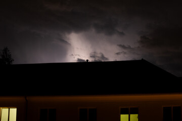 Big thunderstorm up above the city sky illumination with lighting and bolts over the city at night