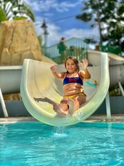 

A young Caucasian girl, around 9 years old, Enjoying Water Slide at Pool on a sunny day.
