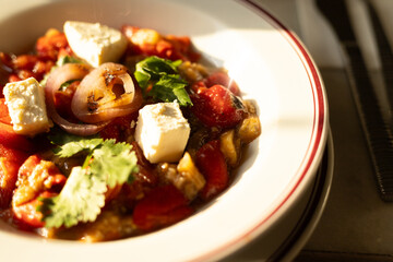 a plate of warm salad with vegetables, cheese and onions