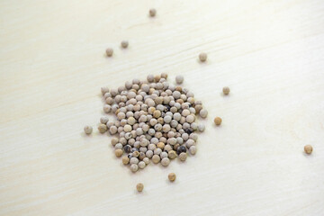 Dry white peppercorn (Piper nigrum) spice seeds on wooden background. © Sahadat
