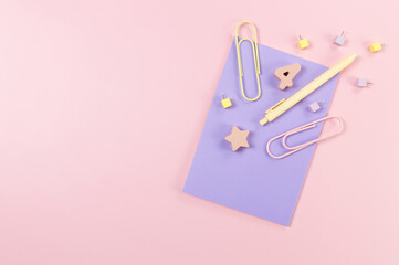 Top view of purple notebook on pink background. Paperclips, pen, number, shape and pins. School, office wallpaper. Flat lay, copy space.