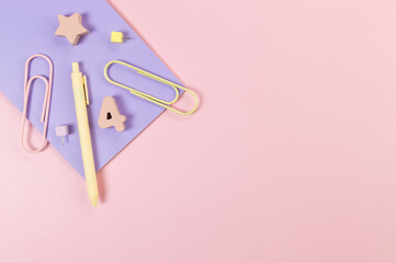 Top view of purple notebook on pink background. Paperclips, pen, number, shape and pins. School, office wallpaper. Flat lay, copy space.
