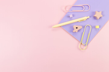 Top view of purple notebook on pink background. Paperclips, pen, number, shape and pins. School, office wallpaper. Flat lay, copy space.