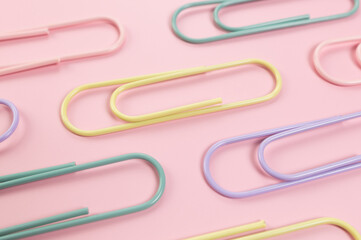 Top view of colorful paperclips on pink background. School, office wallpaper. Flat lay, copy space.