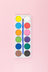 Top view of watercolor and paint brush on pink background. Painting, art, copy space, flat lay.
