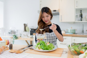 Young asian woman use spoon to adding mayonnaise into salad on plate while preparing fresh...