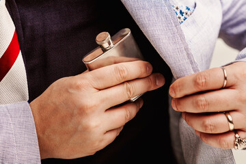 Businessman hiding flask in suit pocket