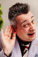 Greedy businessman eavesdropping placing hand on ear