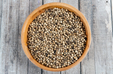 top view of a wooden bowl of coriander seeds on wooden table