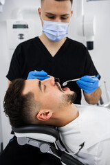 Preventative dental checkup close-up. Dentist uses dental explorer and mirror to advise the patient.