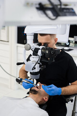 Dentist uses operating microscope to polish teeth of the patient. Operating dental digital...