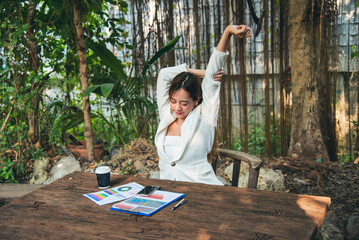 Woman streching arm raised sitting incorrect position home office desk. Back side of young asian...