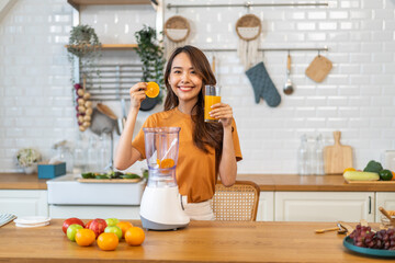 Portrait of beauty healthy asian woman making orange fruit smoothie with blender.girl preparing...