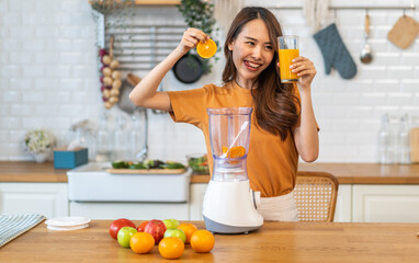 Portrait of beauty healthy asian woman making orange fruit smoothie with blender.girl preparing cooking detox cleanse with fresh orange juice in kitchen at home.health, vitamin c, diet, healthy drink