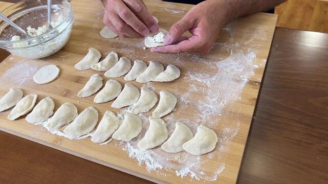 Cooking dumplings, empanadas, vareniki, perogies at home, the man prepares lunch.