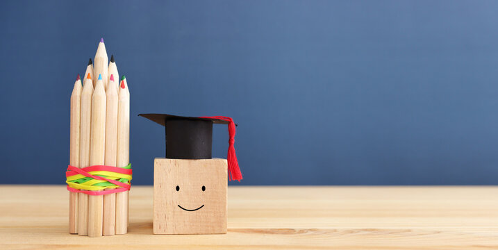 Back to school or education concept. graduation hat on cube with smiling face