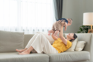 Obraz premium A tiny child smiling happily on the couch in the living room with mom