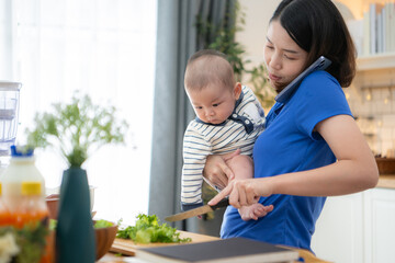 Mother and tiny child in the kitchen preparing dinner