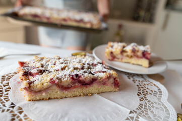 Woman serving homemade plum crumble cake in the kitchen