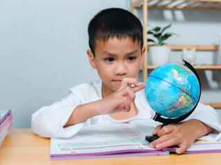 Asian boy looking and point your finger at globe find the location of countries in the world, Concept for research global warming, global network, SEO search engine, Save the Earth, Kid Education.