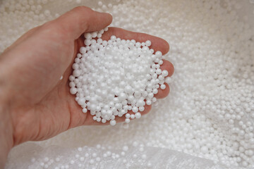 Polystyrene balls in hand. Packaging of fragile goods, filling for chair bags and pillows
