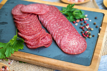 Wooden board with slices of tasty salami 