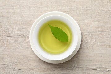 Refreshing green tea in cup on wooden table, top view