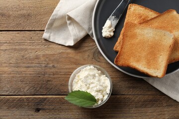 Delicious toasted bread slices with cream cheese, mint and knife on wooden table, flat lay