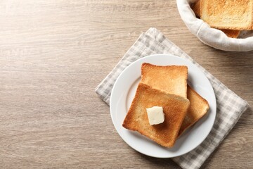 Delicious toasted bread slices with butter on wooden table, flat lay. Space for text