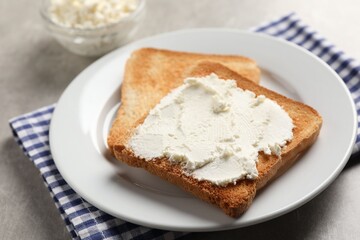 Delicious toasted bread slices with cream cheese on grey table