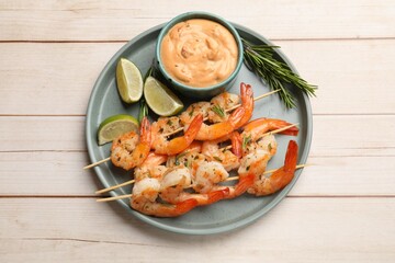 Skewers with delicious grilled shrimps served on white wooden table, top view