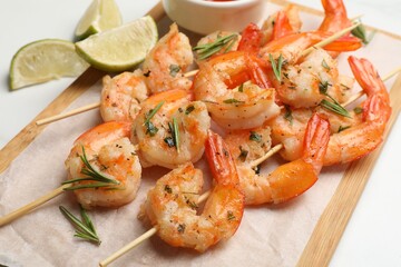 Skewers with delicious grilled shrimps served on white table, closeup