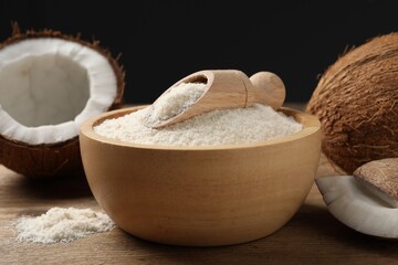Coconut flour in bowl, scoop and fresh fruits on wooden table, closeup