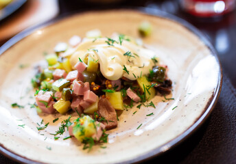 Delicious potato salad with slices of ham and mushrooms close up