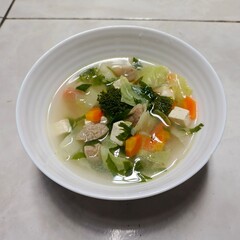 clear soup with sliced meatball, and vegetables. Served in white bowl