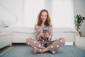 Full body portrait of nice young girl sit floor use phone wear pajama bright interior bedroom flat...