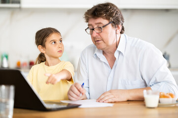 Obraz premium Little daughter shows her father how to use laptop