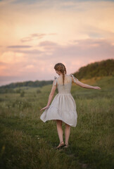 A photo of a beautiful girl against the background of the sunset sky.