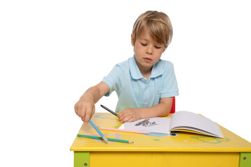 Portrait of a little child drawing, a child sitting at a table with art supplies, drawing on paper.