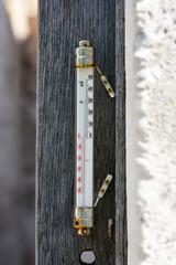 Old thermometer on a wooden plank showing a temperature of 33 degrees Celsius