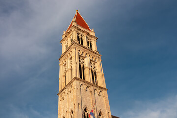 Fototapeta premium Imposing bell tower of Cathedral of St. Lawrence (San Lorenzo) against a dramatic sky in historic old town Trogir, Split-Dalmatia, Croatia, Europe. Tourist travel destination at Adriatic Sea.