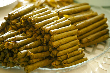 Homemade stuffed vine leaves are arranged in a row on the table,