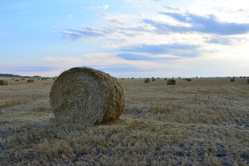a large bale of hay is in a field with a sunset sky in the background 