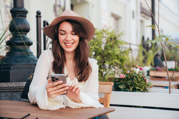 Portrait of beautiful young woman reading text message on mobile phone. Model at coffee shop....