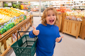 Healthy food for kids. Portrait of smiling little child with shopping bag at grocery store or...