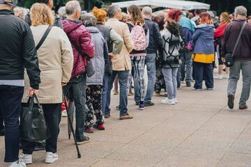 Rear view of queue of unrecognizable people of different genders and ages
