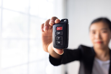 Close up of woman hand holds the car key isolated on a white Blurred background 