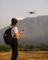 Woman controlling drone with remote controller outdoors. © Evgenii