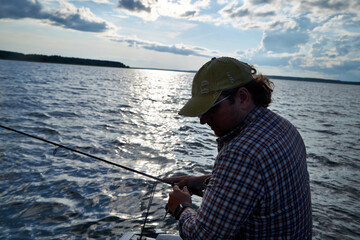 Obraz premium a man in a plaid shirt fishing out of a boat