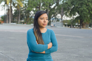 Woman sitting in a public park with her arms crossed in a worried, thoughtful attitude.